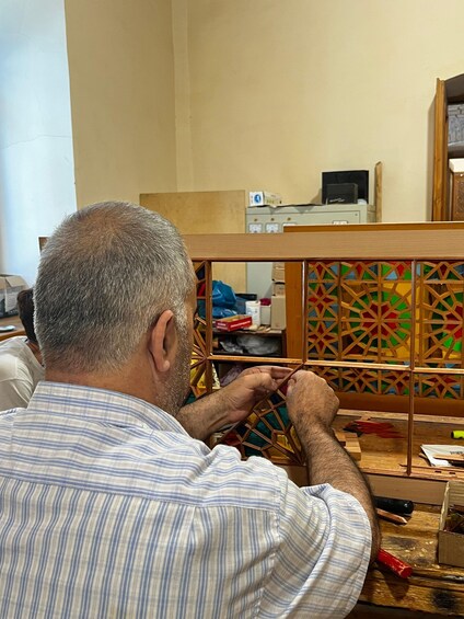 A man working on a wooden structure with geometric patterns. 1