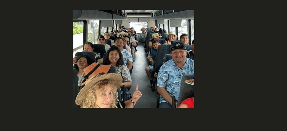 A group of people on a bus, some wearing hats, with a view of the road ahead. 1