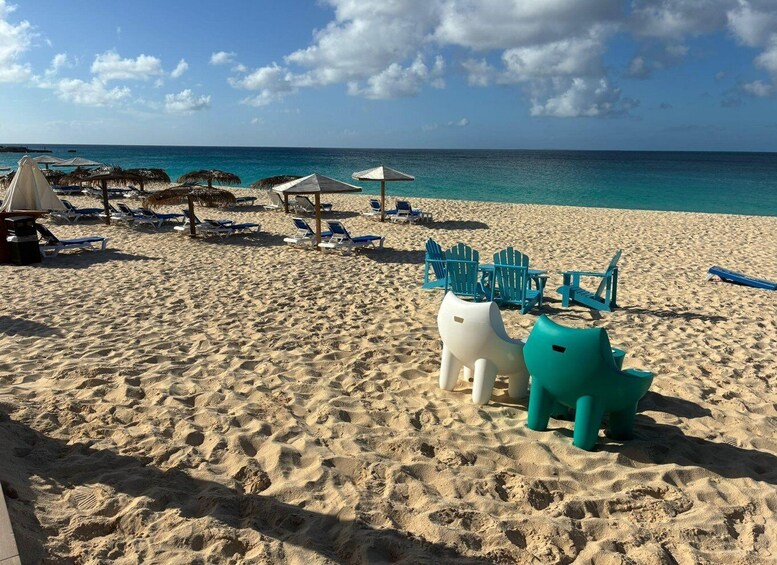 A sandy beach with lounge chairs and umbrellas, a clear blue sky, and the ocean in the background. 3