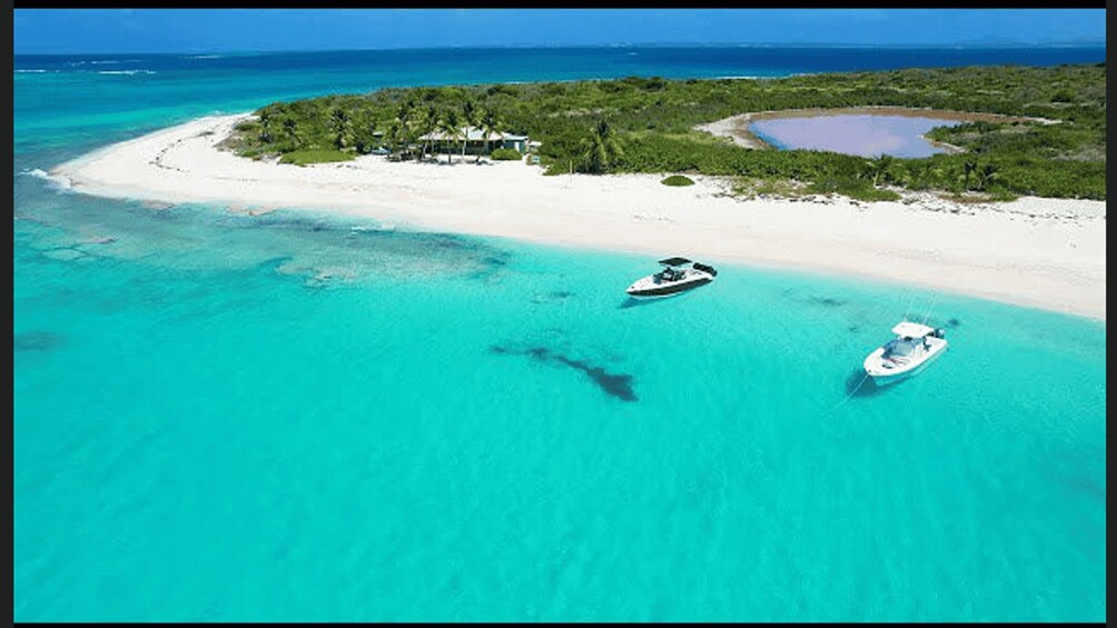 A turquoise sea with two boats and a beach with a small settlement. 2