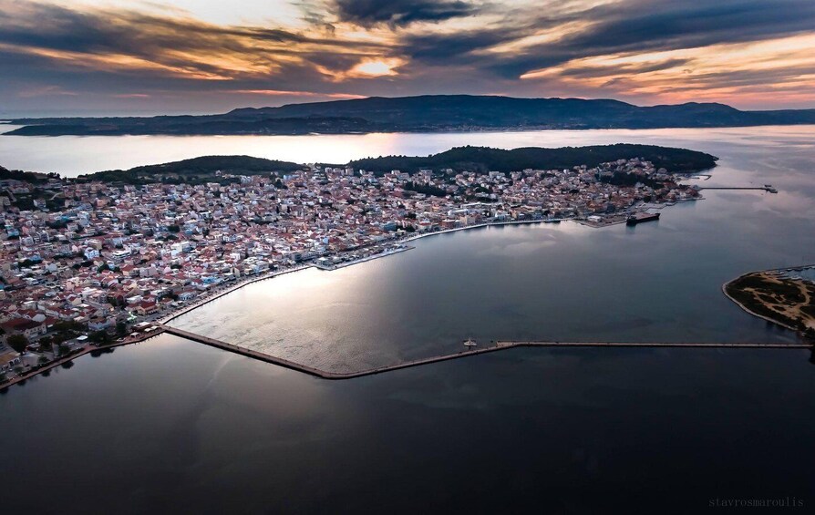 An aerial view of a coastal town with a large body of water, a peninsula, and distant hills. 1