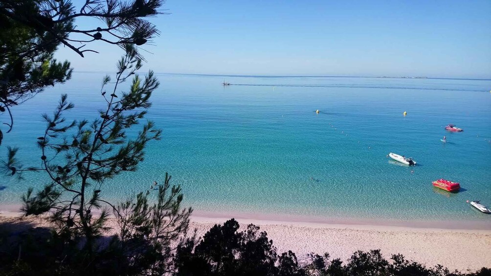 A beach with clear turquoise water, a sandy shore, and a few boats. 4