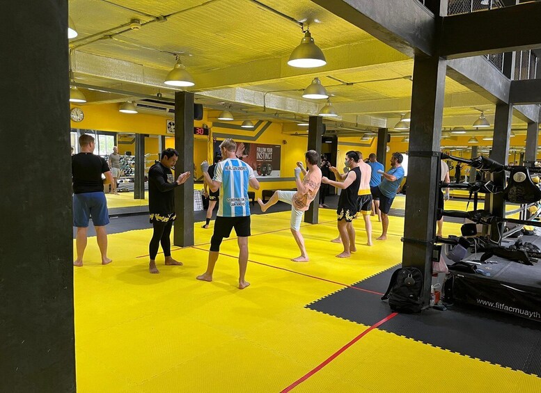 A martial arts training area with yellow mats, punching bags, and a mirrored wall. 2