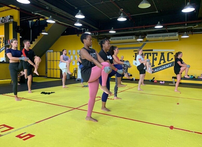 A group of people in a martial arts training session at a gym with yellow walls and mats. 3