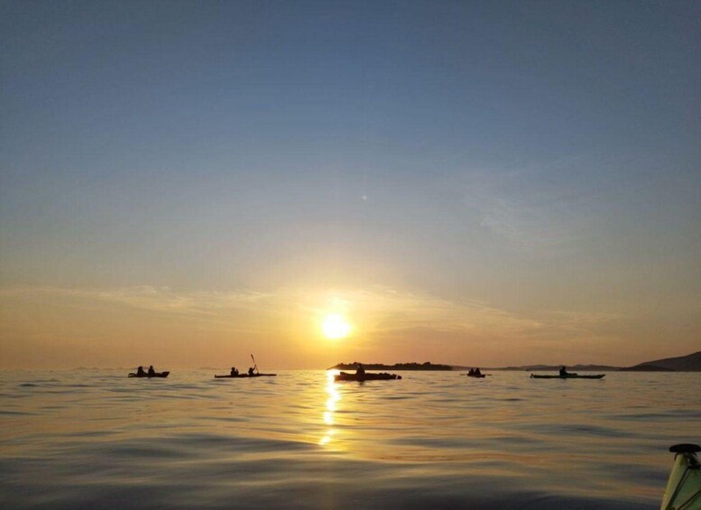 A calm sea at sunset with several boats and a distant shoreline. 4