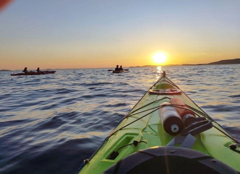 A green kayak on calm water with a sunset in the background. 3