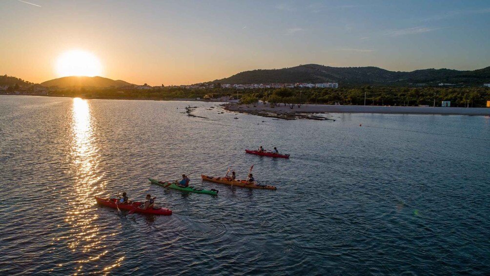 A sunset over a calm body of water with kayaks. 1