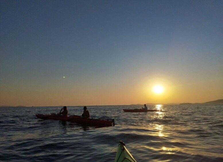 A sunset over calm waters with two canoes and a distant landmass. 5