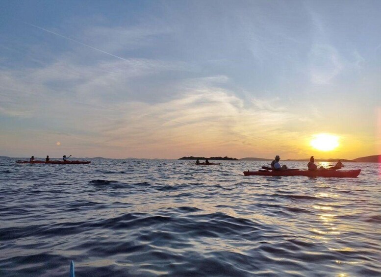 A sunset over calm waters with several kayaks. 2