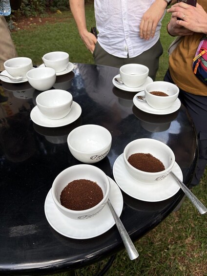 A table with several white cups and saucers, some containing a brown powder, possibly coffee or tea. 5