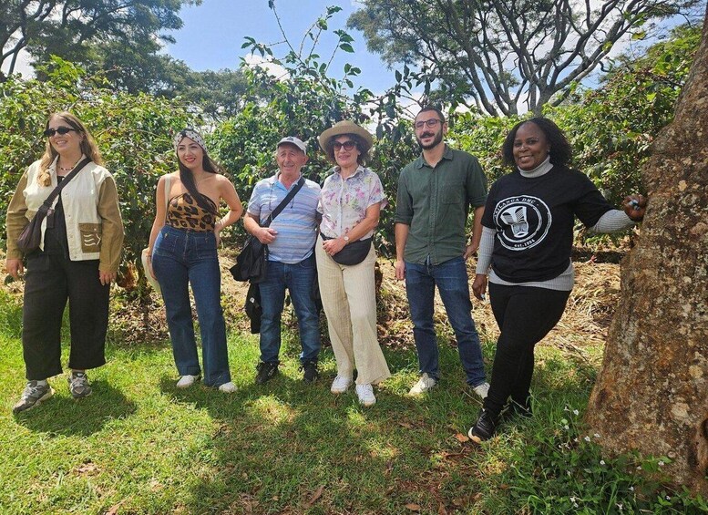 A group of people standing outdoors in a grassy area with trees in the background. 2