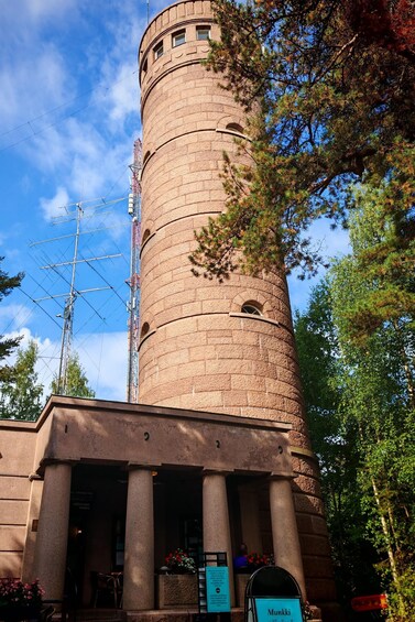 A stone tower with a clock, surrounded by trees and a clear sky. 2