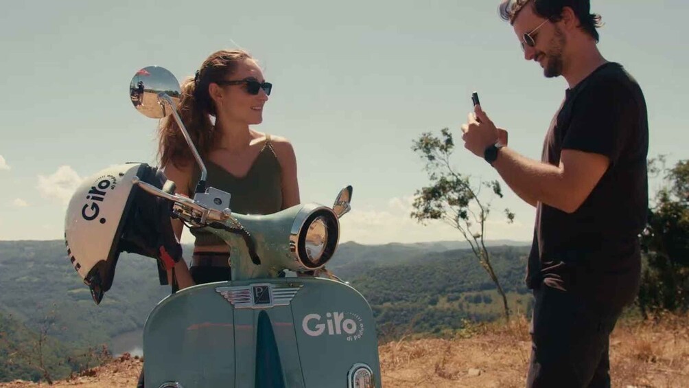 A person pointing at a scooter with a 'Giro' logo, another person with a helmet, and a scenic landscape in the background. 3