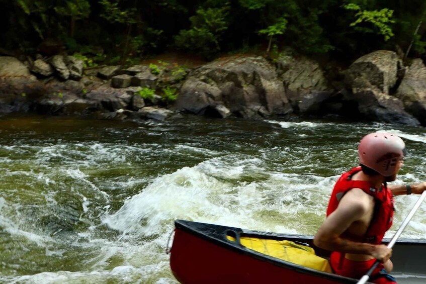 A person in a red kayak navigating a river with white water rapids. 3