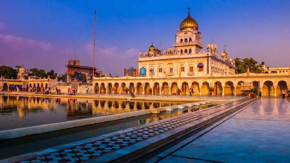 A historic building with a large dome and arches, surrounded by a reflective water body. 2