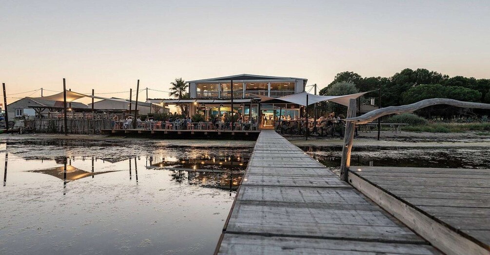 A waterfront restaurant with outdoor seating and a wooden walkway leading to it. 5