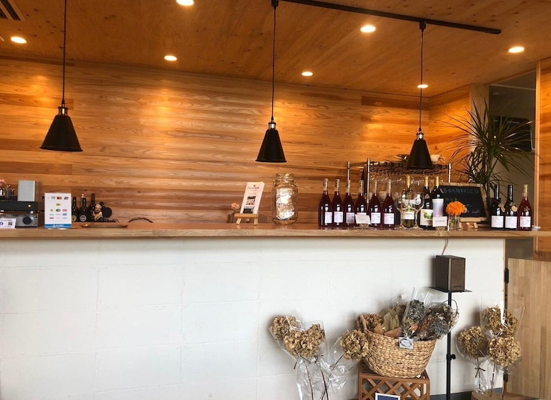 A wooden bar counter with hanging pendant lights, bottles of wine, and a chalkboard menu. 5