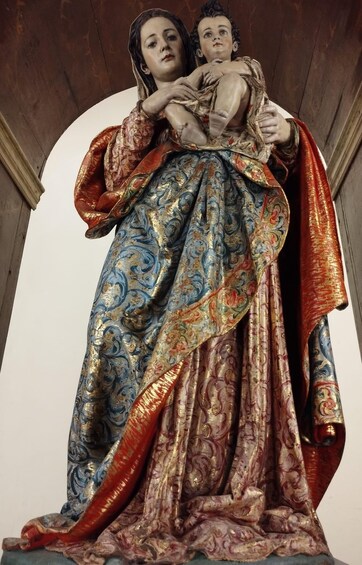 A statue of a woman holding a child, both adorned in elaborate robes with intricate patterns. 5