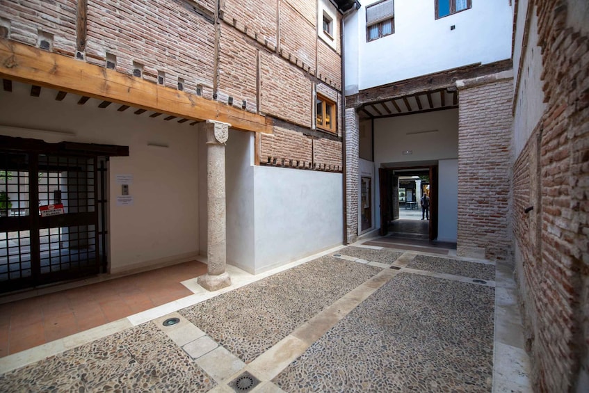 A courtyard with a brick building, a wooden beam structure, and a tiled floor. 1