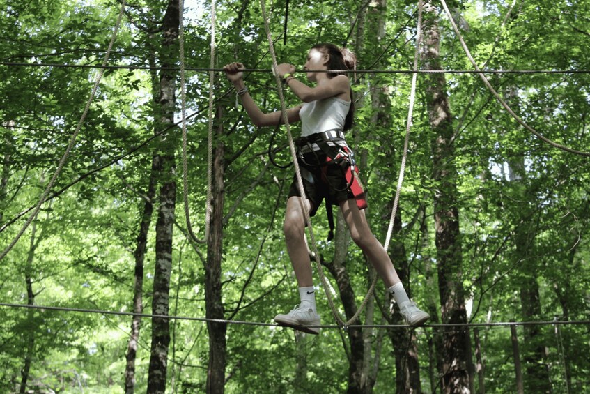 A person navigating a rope course in a forest. 3