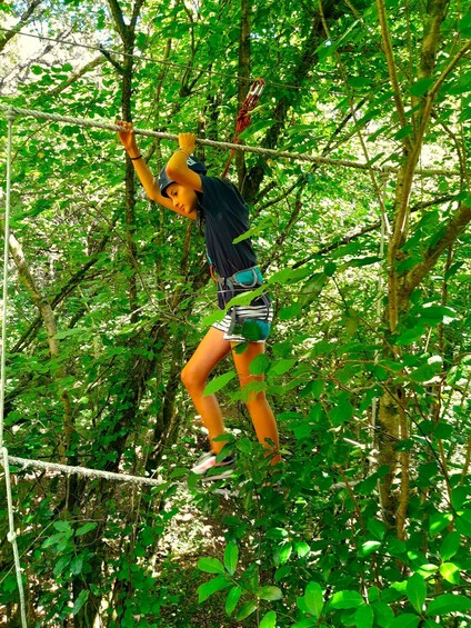 A person climbing a rope bridge in a forest. 2