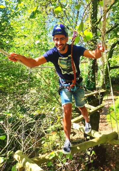 A person on a rope bridge in a forest. 4