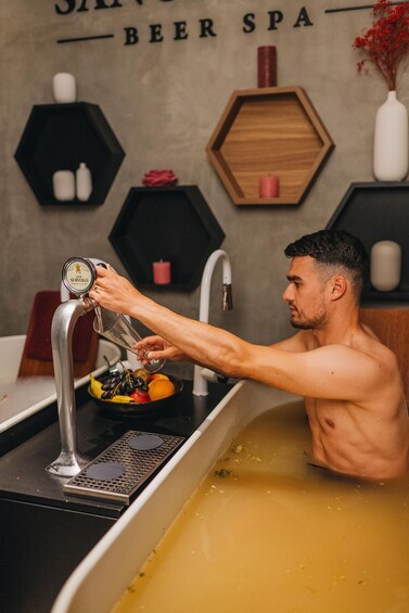 A person pouring beer into a bathtub filled with a yellowish liquid. 3