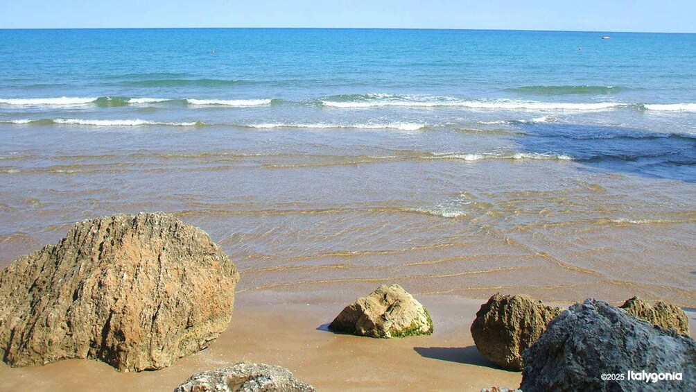 A beach with large rocks and calm waves. 4