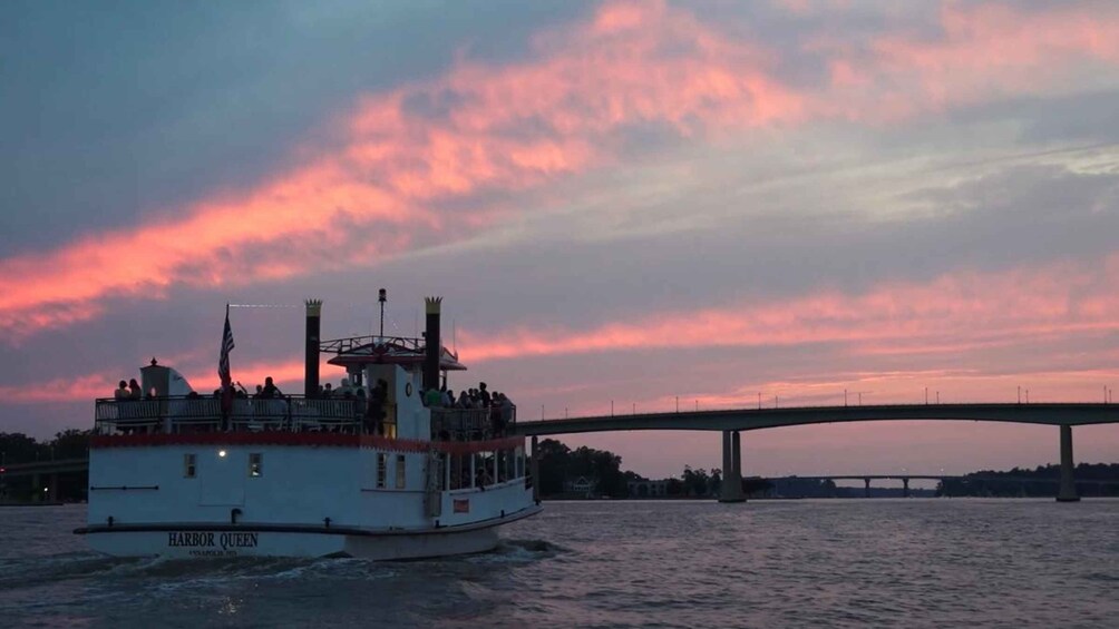 A boat named Harbor Queen on a river with a bridge in the background. 2