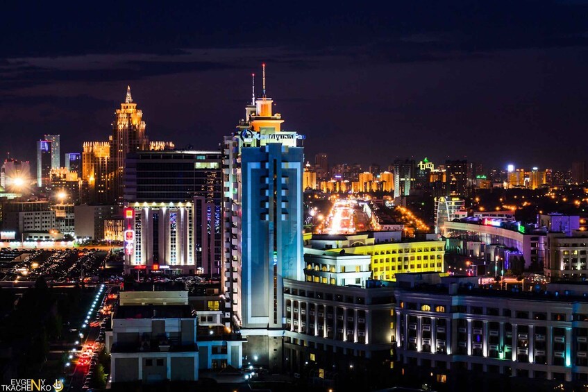 A cityscape at night with illuminated buildings and a busy street. 3
