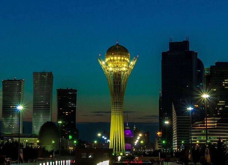 A cityscape at night with a prominent tower featuring a spherical top and a spire, surrounded by modern skyscrapers. 4