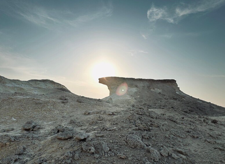 A desert landscape with a prominent rock formation and a clear sky. 5