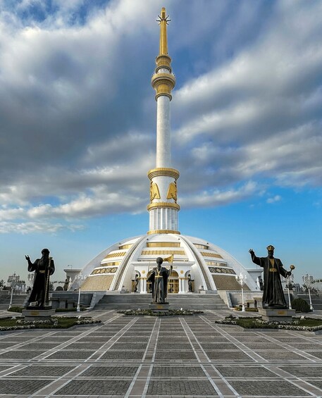 A large white monument with a golden spire, surrounded by statues and a tiled plaza. 2