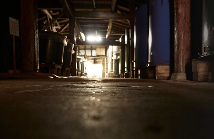 An indoor corridor with wooden beams, a polished floor, and a bright light source at the end. 3