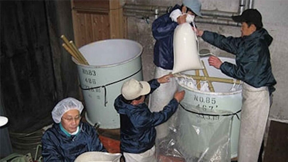 People handling large containers, possibly in a storage or industrial setting. 4