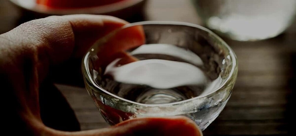 A hand holding a clear glass bowl with a liquid. 1