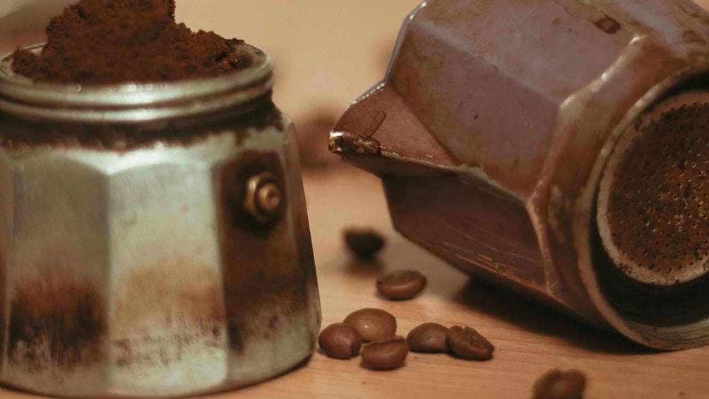 A coffee grinder and a metal container with coffee beans on a wooden surface. 3