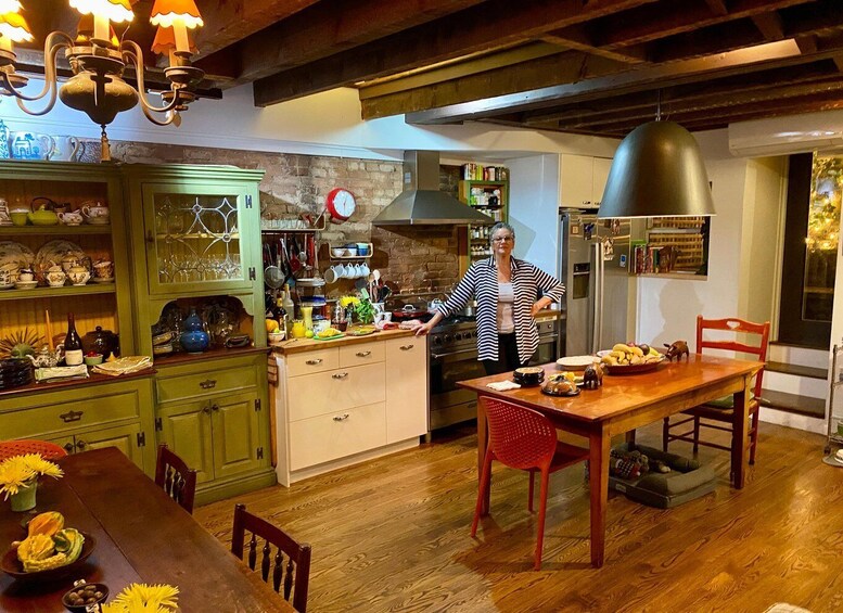 A kitchen with wooden floors, a dining table, and a person cooking. 2