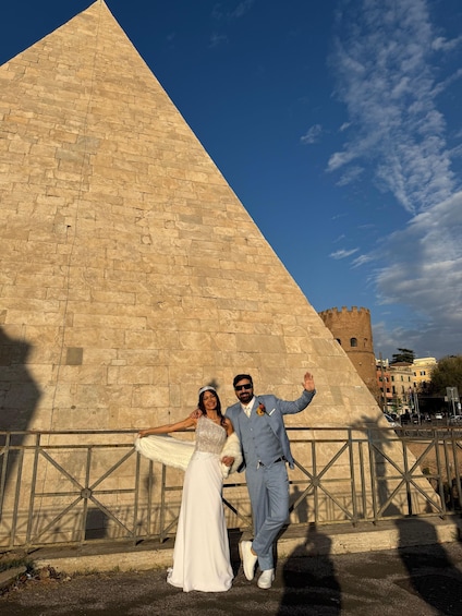 A couple posing in front of a large stone pyramid with a castle in the background. 1