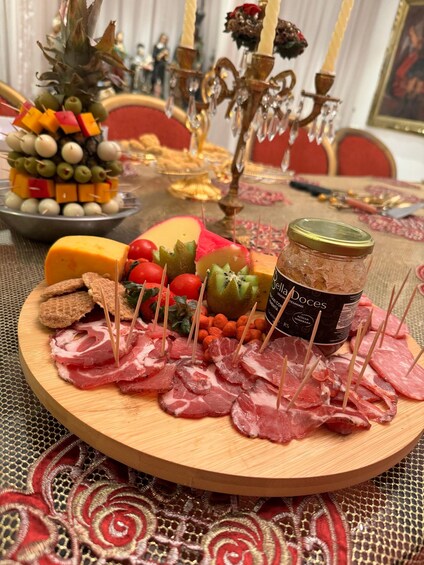 A wooden board with various cheeses, fruits, and cured meats. 5
