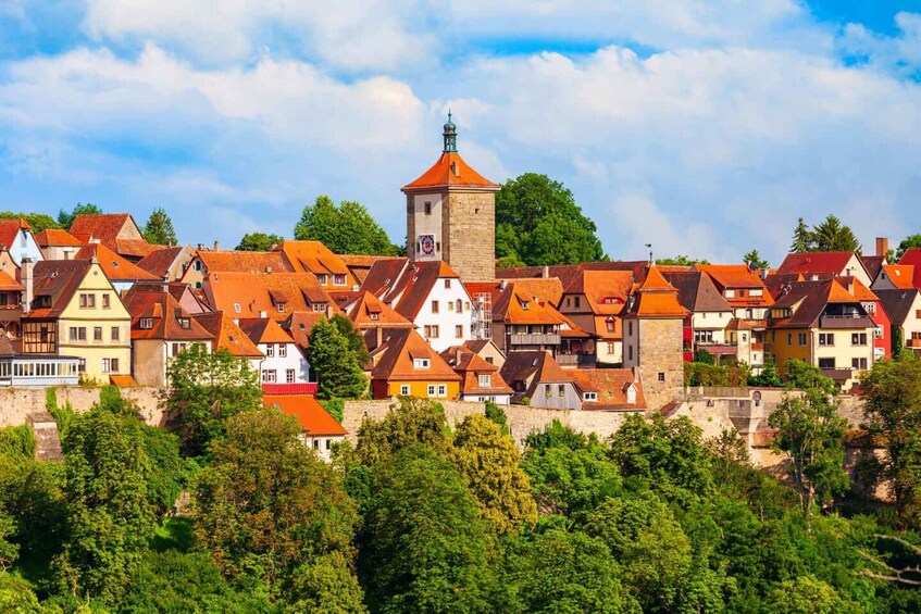 A historic town with red-roofed buildings, a prominent tower, and lush greenery. 2