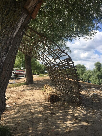 A wooden structure under a tree, a sandy ground, and a fence in the background. 2