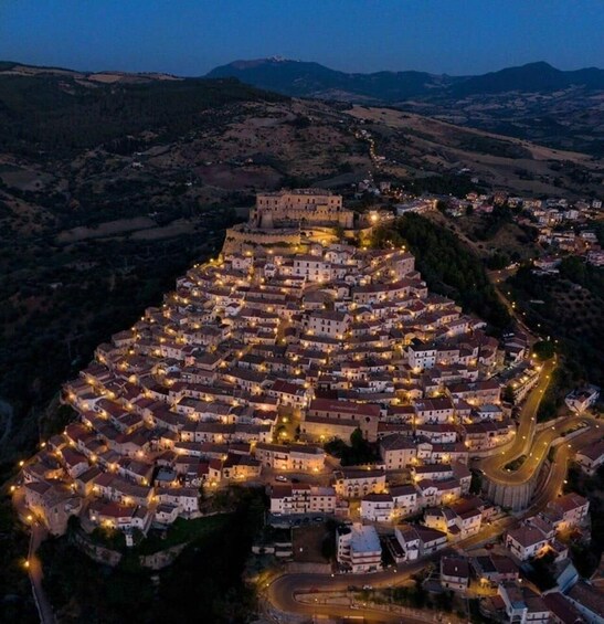A town at dusk with illuminated buildings and winding roads. 3