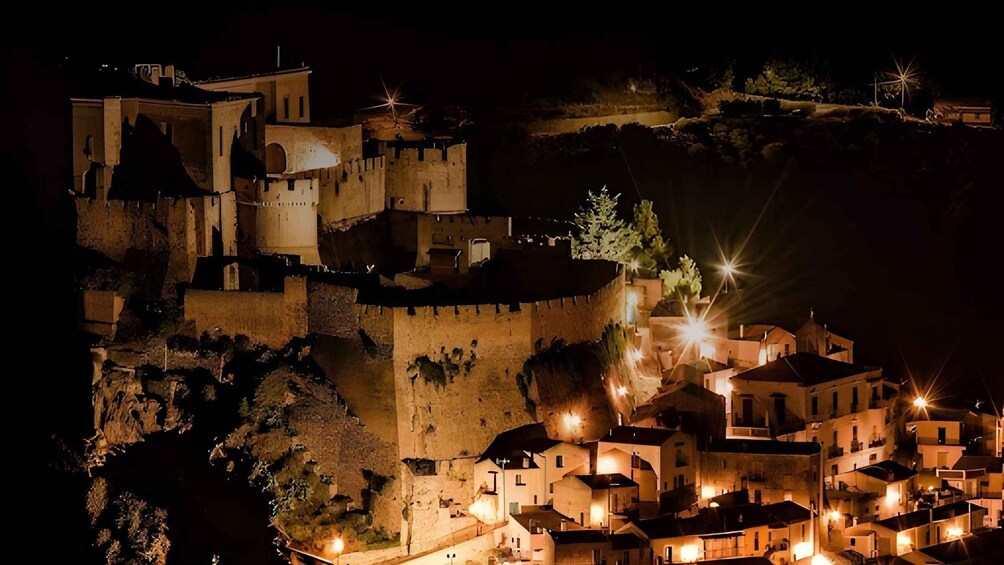 A medieval castle with illuminated rooftops and a fortified wall. 1