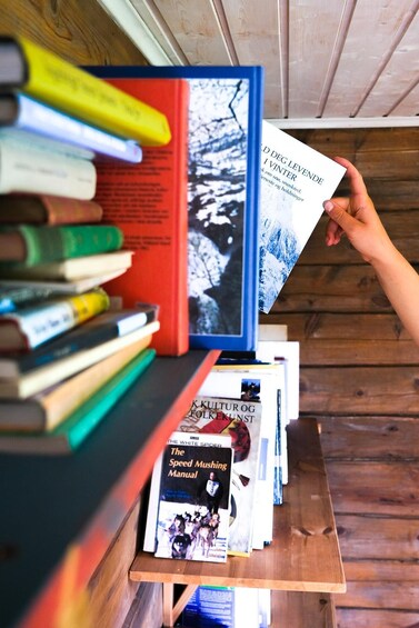 A hand holding a book titled 'I VINTER' with a snowy landscape on the cover. 5