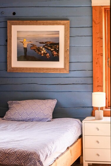 A bedroom with a bed, a nightstand, a lamp, and a framed picture on the wall. 3