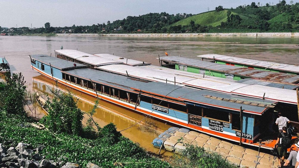 A riverboat docked at a riverbank with a hilly landscape in the background. 1