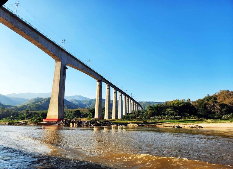 A long bridge spanning a river with mountains in the background. 2