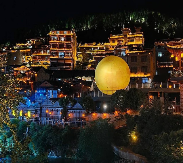 A traditional village at night with illuminated buildings and a large yellow sphere. 5