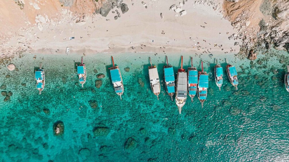 A beach with boats docked in clear turquoise water. 2